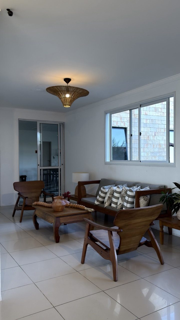 Sala de estar com poltronas de madeira maciça, sofá e luminária de palha